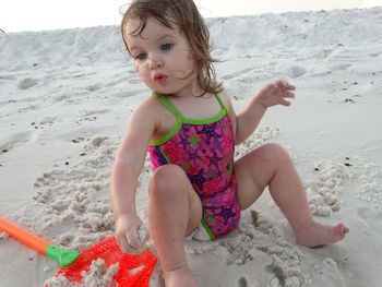 Cute girl playing on sand at beach