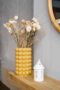 Dried flowers in a yellow vase on a wooden shelf. a bouquet of dried flowers on the countertop 