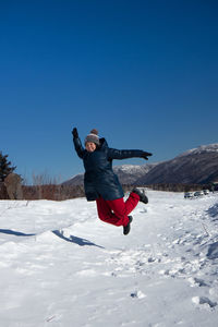 Full length of man jumping on snow