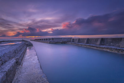 Bridge over sea against sky during sunset