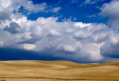 Scenic view of desert against cloudy sky