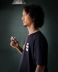 Side view of young man looking away against gray background