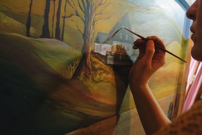 Cropped image of woman drawing on canvas in cottage