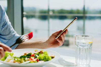 Midsection of person holding ice cream on table