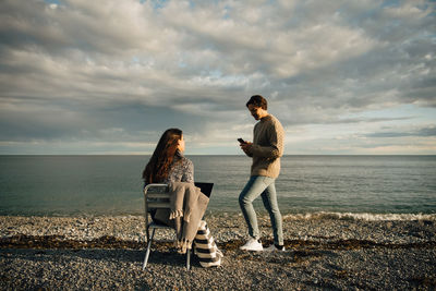 Woman standing at sea shore against sky