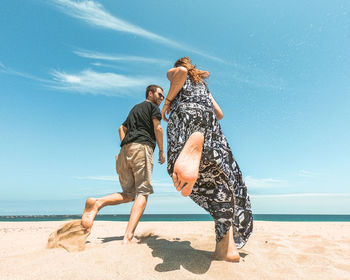 Rear view of people on beach against sky