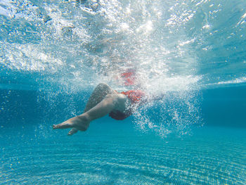 Girl swimming underwater in swimming pool