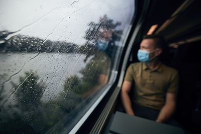 Woman seen through wet window in rainy season