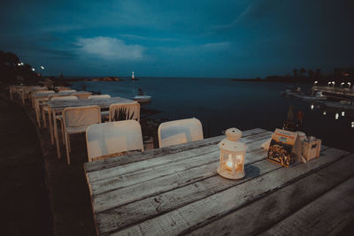 Empty tables and chairs by sea at dusk