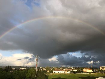 Rainbow over buildings in city against sky