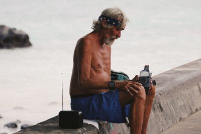 Man using mobile phone while sitting against sky