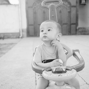 Cute baby boy sitting on stroller in back yard