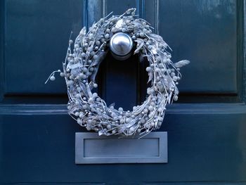 Silver christmas wreath hanging on deep blue front door