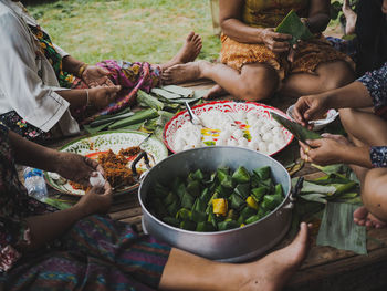 Low section of women preparing food while sitting outdoors