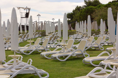 Close-up of empty chairs on field against sky