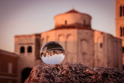 Close-up of crystal ball by building against sky