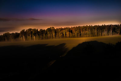 Silhouette trees on landscape against sky during sunset