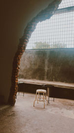 Empty chairs and table against wall in building