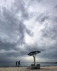 Men standing on beach against sky