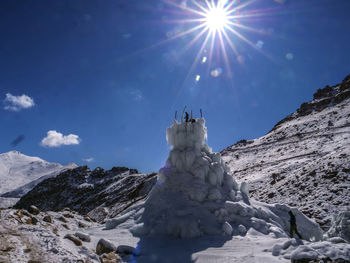 Low angle view of snowcapped mountains against blue sky on sunny day