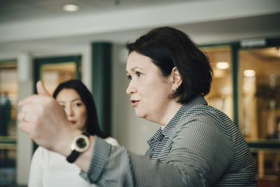 Confident businesswoman gesturing while explaining during conference event in office