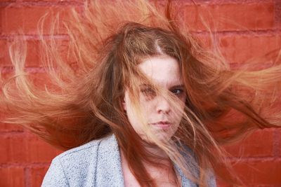 Portrait of beautiful woman with messy hair against wall