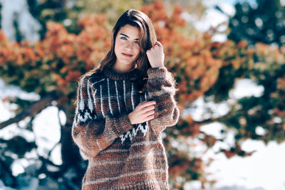 Portrait of smiling woman standing against trees during winter