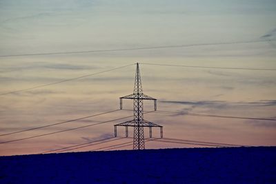 Electricity pylon against cloudy sky