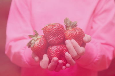 Midsection of child holding strawberries