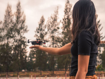 Woman holding drone while standing outdoors