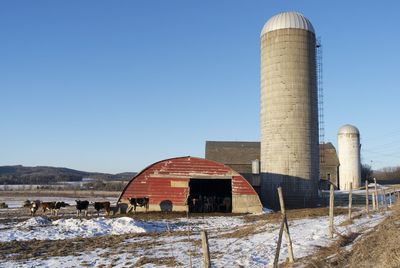 Low angle view of silo at farm against clear blue sky during winter