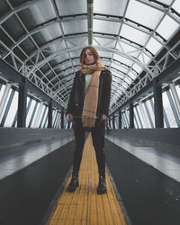 Portrait of young woman standing on footbridge