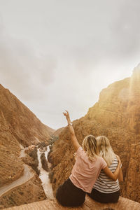 Rear view of woman on rock against sky