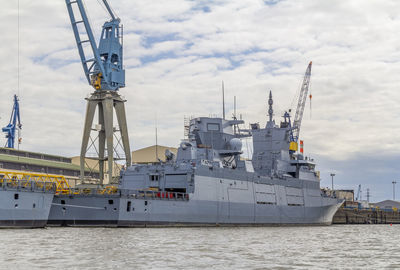 Cranes at commercial dock against sky