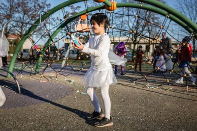 Standing girl in angel carnival costume in the park having fun