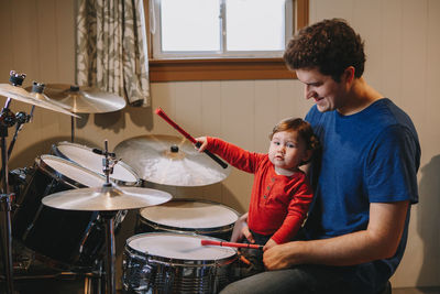 Smiling man looking at son holding drumstick