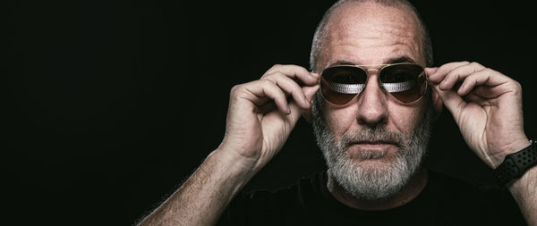 Portrait of man wearing sunglasses against black background