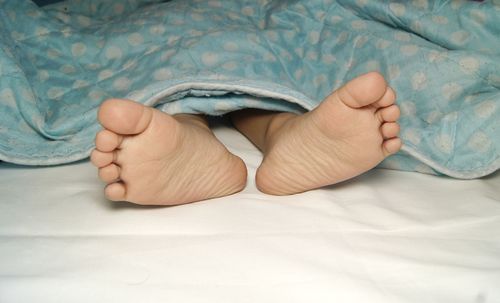 Low section of baby lying on bed