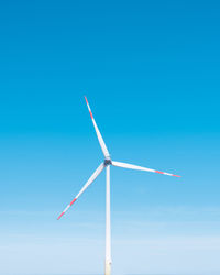 Low angle view of wind turbine against clear blue sky