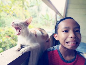 Boy making face by cat on wall