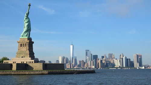 Statue of liberty against sky and city buildings