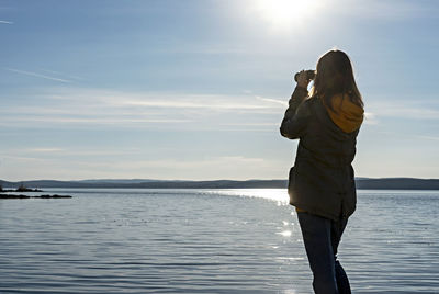 Woman standing by sea against sky