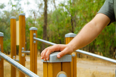 Midsection of hand on railing against trees