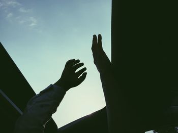 Low angle view of silhouette hand against sky