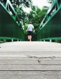 Rear view of man walking on footbridge