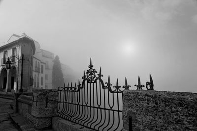 Fence by building against sky