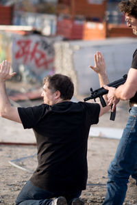 Criminal with gun pointing at man kneeling on field