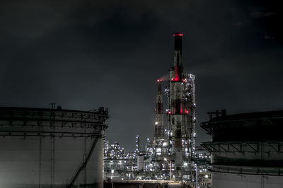 Illuminated factory against sky at night