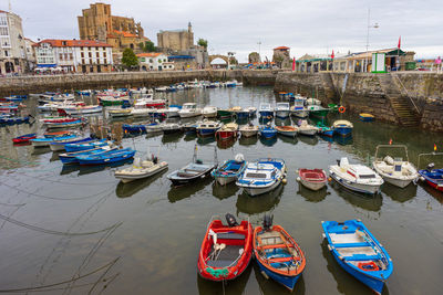 High angle view of boats moored at harbor by buildings in city