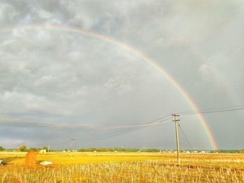 Scenic view of field against rainbow in sky